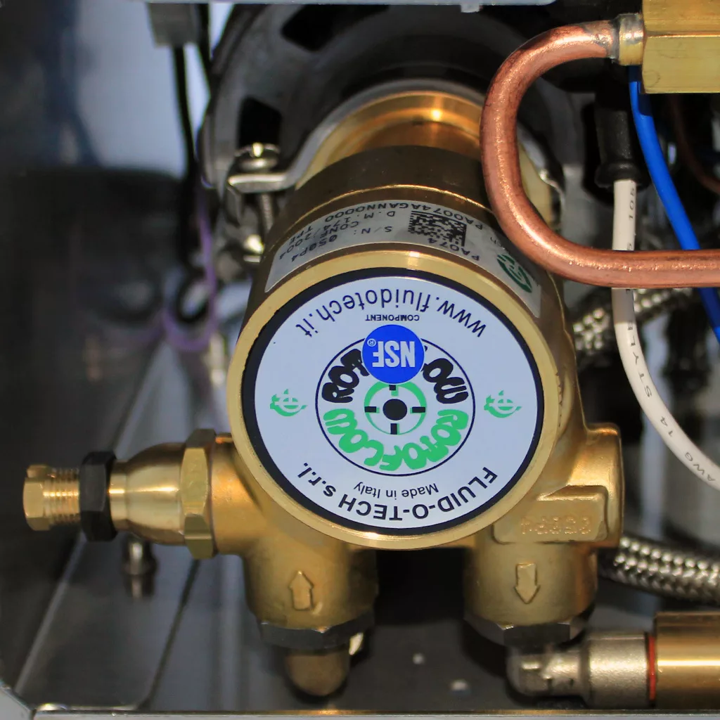 Close-up of a brass Fluid-o-Tech NSF fluid control valve attached to copper and silver pipes inside a discontinued VBM Domobar Super V4 Dual Boiler PID Switchable Espresso Machine. © 2025 1st-line.com