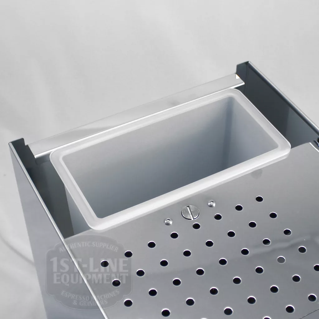 A close-up of the drip tray on the DISCONTINUED ECM Classika PID Espresso Machine, showing its removable plastic container and perforated stainless steel with circular drainage holes. © 2025 1st-line.com