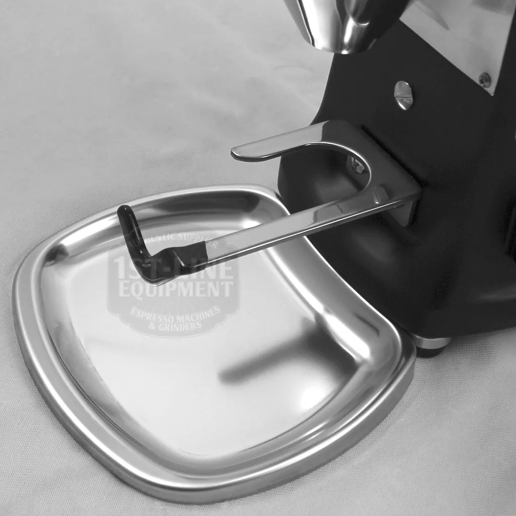 A close-up of the DISCONTINUED Mazzer Mini Type A Espresso Coffee Grinder (old style) shows its portafilter holder and metal drip tray on a light surface, with focus on these components. © 2025 1st-line.com