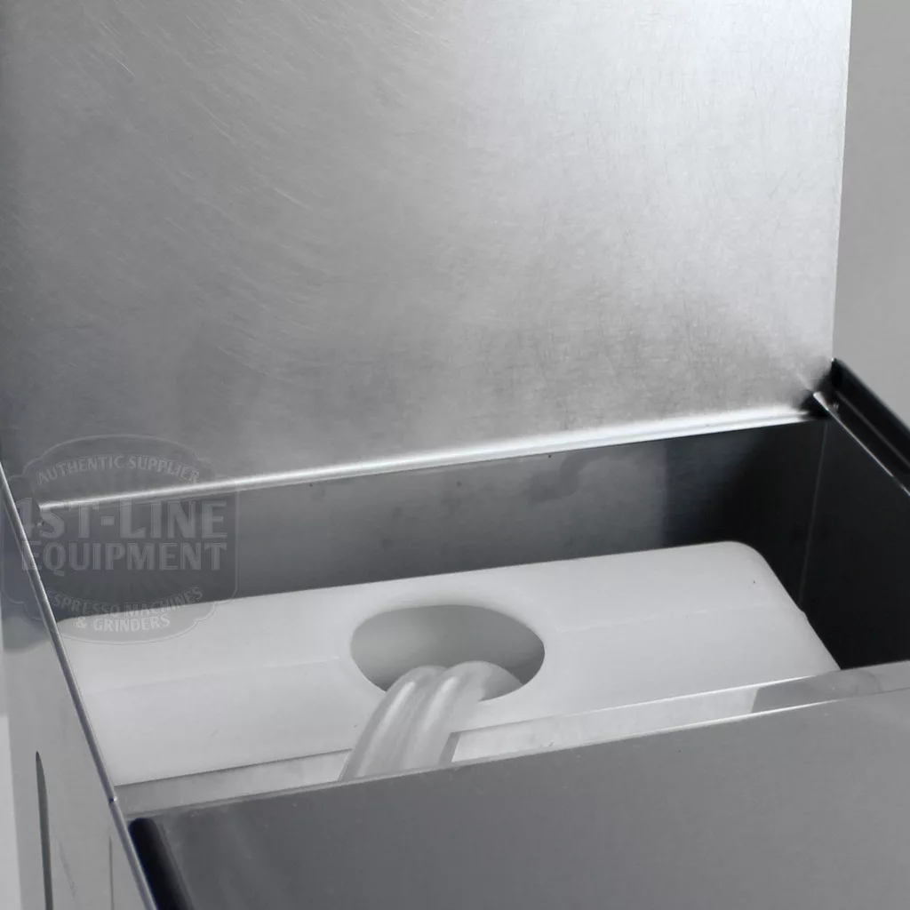 Close-up of a metal container inside the Lelit PL41TEM Anna PID Espresso Machine, showing an open lid that reveals a white plastic tank with a circular opening and clear tube in its clean, industrial interior. © 2025 1st-line.com