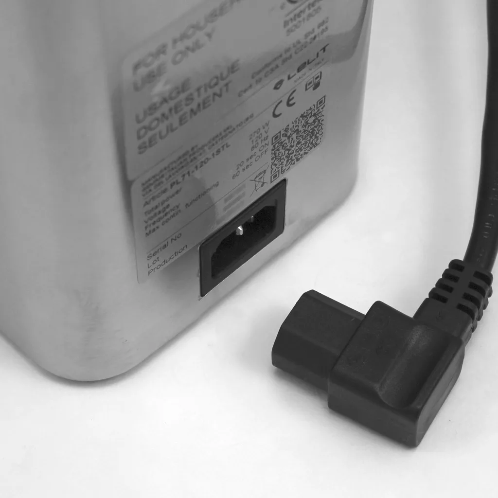 A close-up of a power cord next to the socket of a metallic appliance, identified as a DISCONTINUED Lelit PL71 William Espresso Coffee Grinder, with visible warning and usage labels above the socket. © 2025 1st-line.com