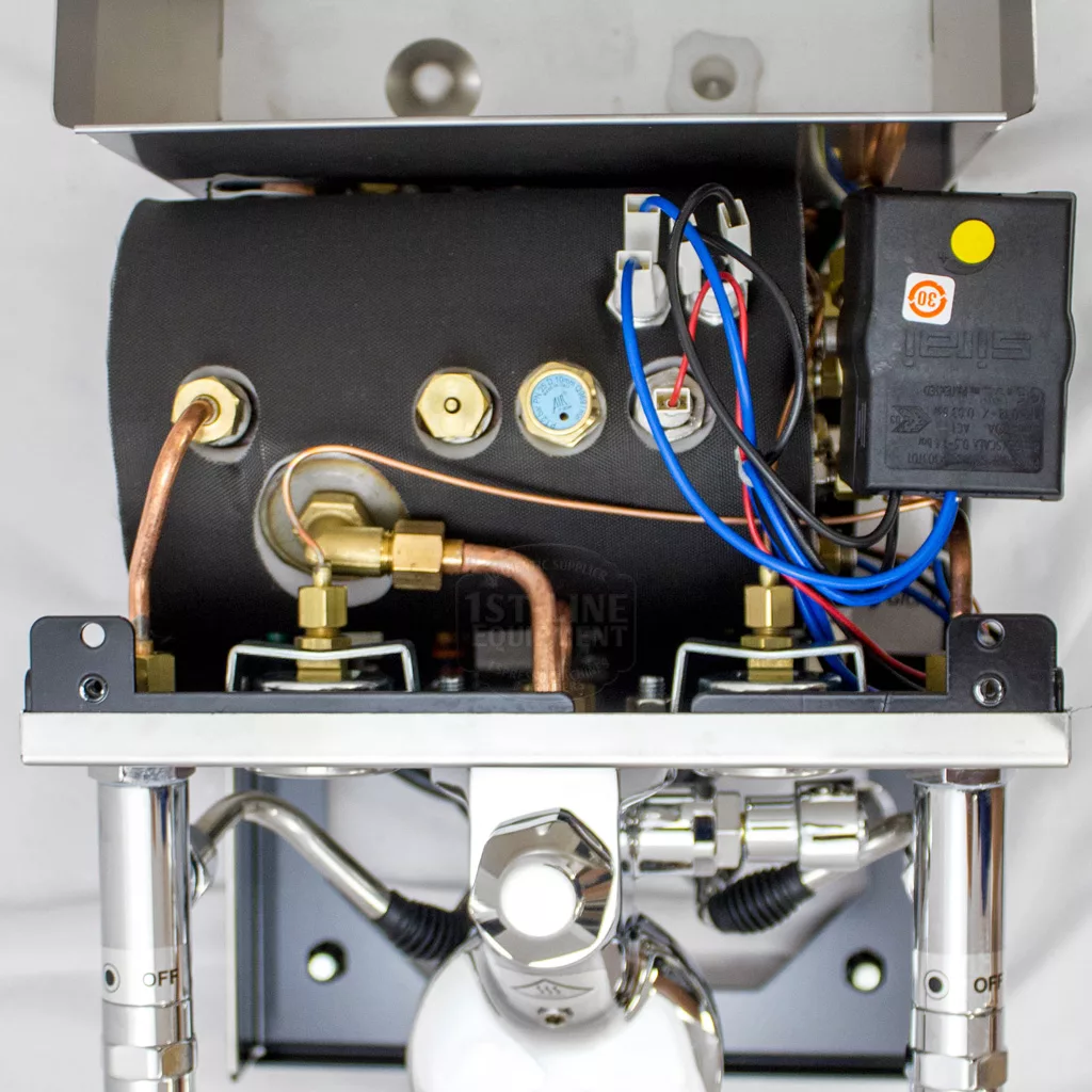 Close-up of the internal components of the DISCONTINUED ECM Mechanika Profi IV Switchable Espresso Machine, featuring copper pipes, a black cylindrical boiler, valves, connectors, wiring, and a labeled control unit with colored wires. © 2025 1st-line.com