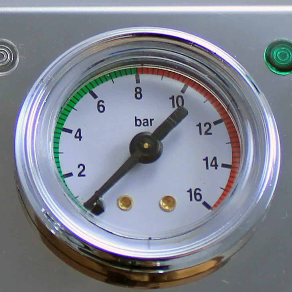 A close-up of a pressure gauge on the DISCONTINUED VBM Domobar Super V4 Dual Boiler PID Switchable Espresso Machine shows about 10 bar, with a dial featuring green, white, and red zones (0–16), a metallic background, and a green indicator light. © 2025 1st-line.com