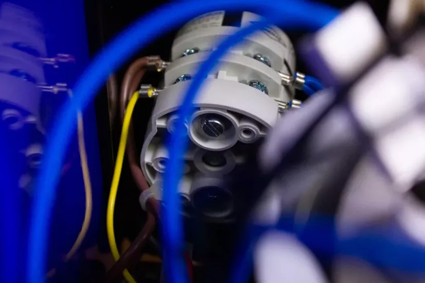 Close-up of internal components in the DISCONTINUED ECM Controvento Dual Boiler PID Switchable Espresso Machine (110V), showing blue, brown, and yellow wires connected to gray connectors and metal screws; foreground is slightly blurred. © 2025 1st-line.com