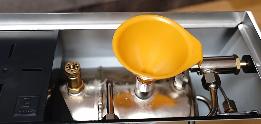 A close-up of a DISCONTINUED Ponte Vecchio Lusso 1 Group Spring Piston Lever Espresso Machine’s internal parts, featuring a yellow funnel placed in the boiler opening to easily pour in water. © 2025 1st-line.com