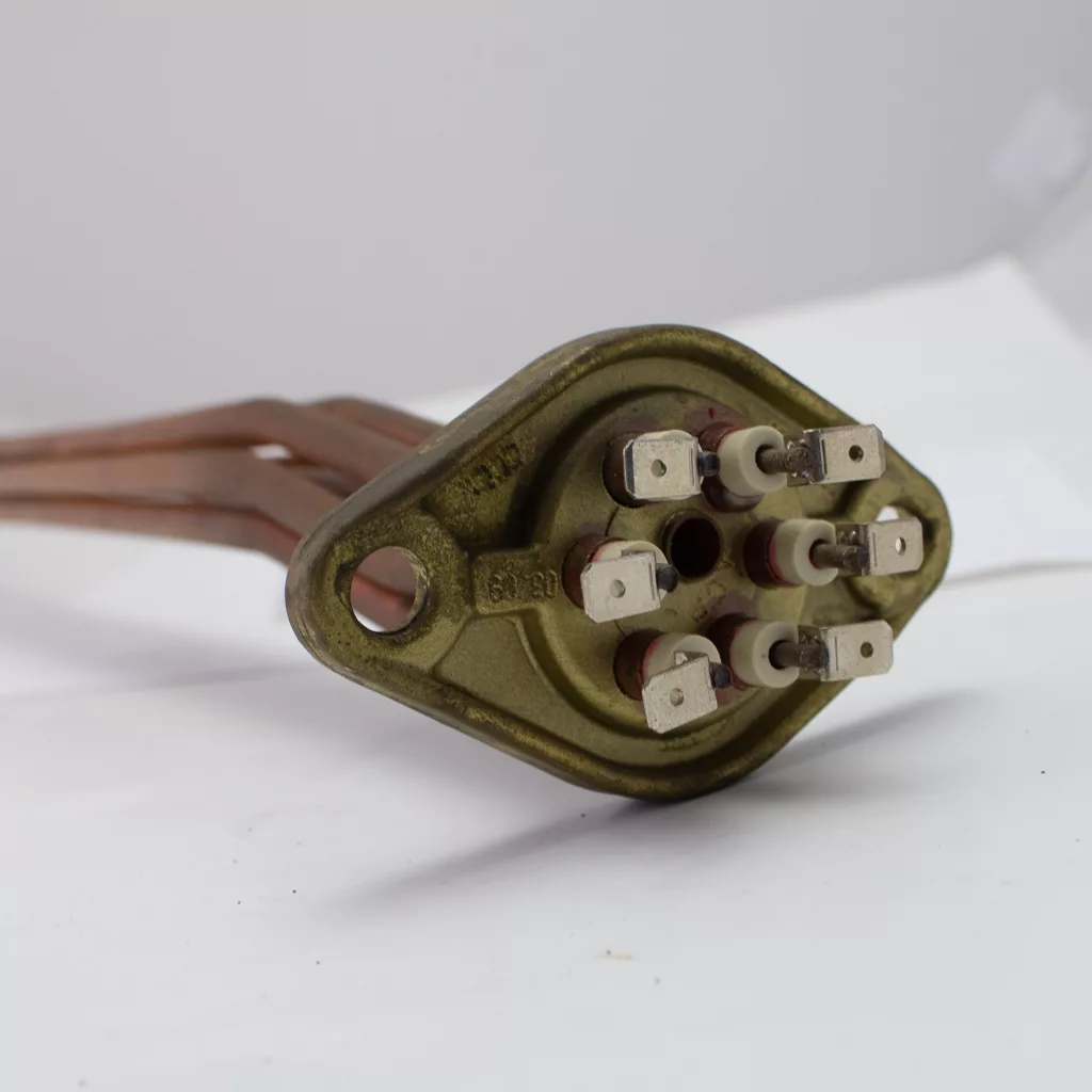 A close-up of the Fiorenzato A1200120 Group Heating Element, 230v, 4000 watts, featuring six terminals on a brass flange and three copper tubes extending from the base, displayed on a white surface. © 2025 1st-line.com