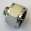 A close-up of the Grimac MG186 Reducer 3/8 x 1/8 F-M metallic hexagonal fitting on a white background, showing its external threads on one end and a wider open side on the other. © 2025 1st-line.com