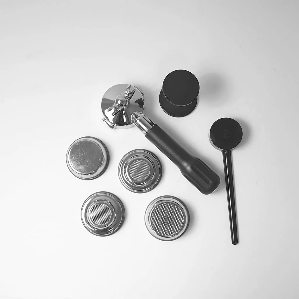 A flat lay of coffee-making tools, including a portafilter with black handle, tamper, dosing tool, and four metal filter baskets on a white background—ideal accessories for your Lelit PL41TEM Anna PID Espresso Machine. © 2025 1st-line.com