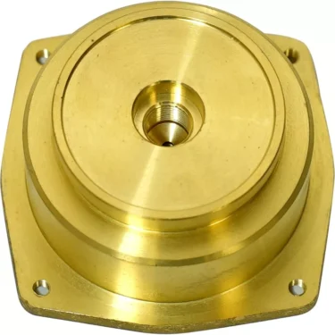 A gold-colored metal flange from the Lelit MC136 Lower Boiler Body features a circular, layered design with a central threaded hole and four mounting holes at the corners. © 2025 1st-line.com