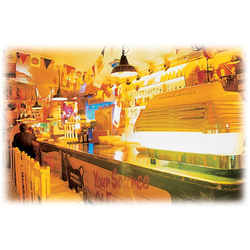 A man sits at a restaurant counter, with a white ice REDIRECTED Elektra Classic Barlume Commercial Espresso Machine (2 group) gleaming behind him. © 2025 1st-line.com