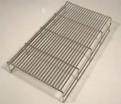 A metal cooling rack with parallel wires and four raised legs, similar to the Fiorenzato A1800176 Grid for Drip Tray for Bricoletta/Volante Tank/Reservoir Model Only, is typically used for cooling baked goods. © 2025 1st-line.com