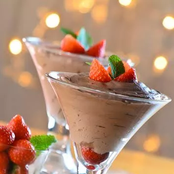 Chocolate mousse made with DISCONTINUED Antico Eremo Chocolate Mousse dessert powder mix 2.2lb bag, served in martini glasses and topped with strawberries and mint, with extra garnishes and warm, blurred lights in the background. © 2025 1st-line.com