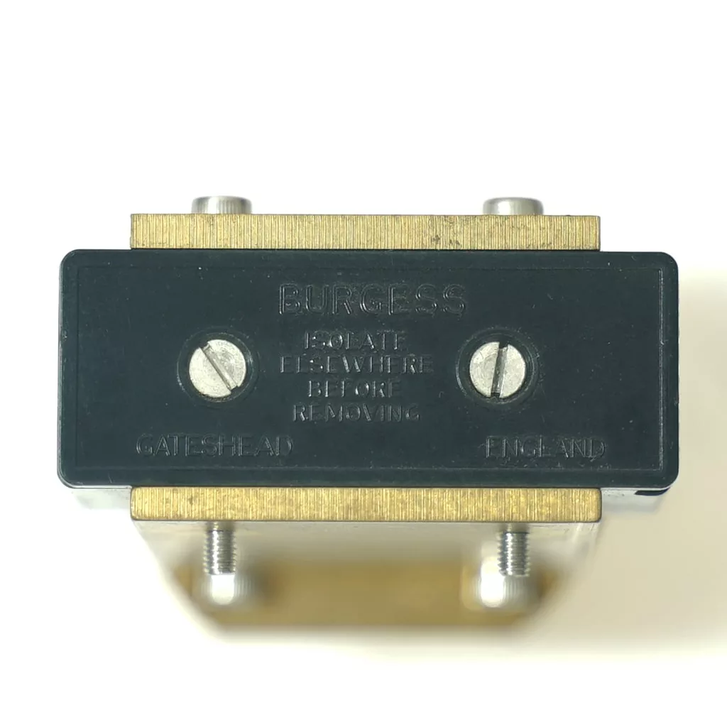 Close-up of a black and brass OEM Olympia Pressurstat labeled BURGESS with two screws and engraved text: ISOLATE ELSEWHERE BEFORE REMOVING, plus GATESHEAD and ENG. XNL at the bottom. © 2025 1st-line.com