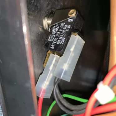 Close-up of a VBM ELETMICREKIRI Microswitch labeled MDX-1040LM, wired with red, black, yellow, and green cables inside an electronic device. © 2025 1st-line.com