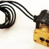 Close-up of a VBM UNK61559532 3-Way Solenoid Valve with a black coil, electrical wires, and a rectangular brass base featuring two circular openings. © 2025 1st-line.com