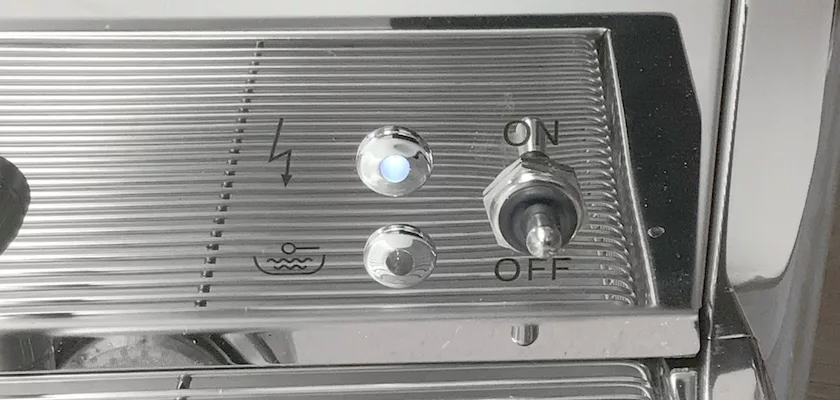 Close-up of the control panel of a DISCONTINUED Bezzera BZ16 DE HX Espresso Machine, showing a power symbol, illuminated button, water symbol, and an ON/OFF toggle switch set to ON. © 2025 1st-line.com