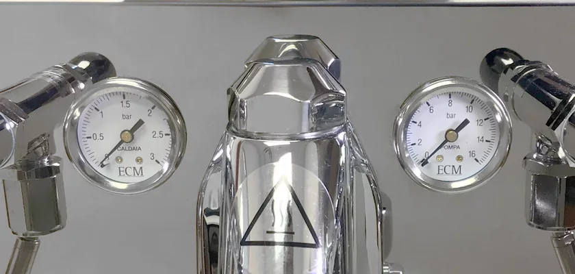 Close-up of the discontinued ECM Elektronika II Profi HX Espresso Machine, showing dual pressure gauges for CALDAIA and OMPRA (in bars), sturdy side handles, a central warning symbol, and classic Profi HX styling. © 2025 1st-line.com