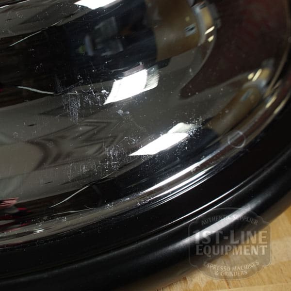 Close-up of the reflective chrome surface on the SIDEWALK SALE - Elektra Mini Verticale A1C Espresso Machine (E211), showing scratches, smudges, part of a circular black rim, and a faint 1st-Line Equipment logo in the bottom right. © 2025 1st-line.com