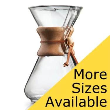 The Chemex Classic Series Coffeemaker with a wooden collar and leather tie is shown against a white background, with a yellow triangle in the lower right corner that reads: More Sizes Available. © 2025 1st-line.com