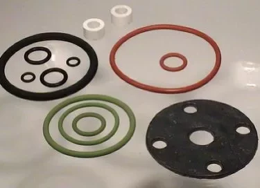 The Elektra 01931034 Semiautomatica Full Gasket Kit includes assorted O-rings and gaskets in black, red, green, plus white spacers and a black flange—all displayed on a flat surface in different sizes and colors. © 2025 1st-line.com