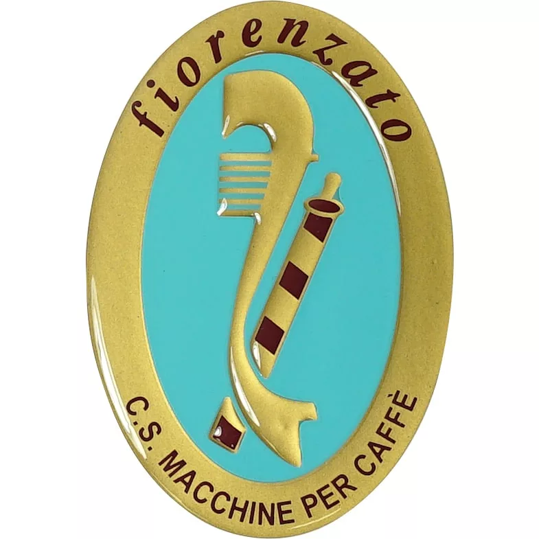 The Fiorenzato A2400044A Logo Emblem showcases an oval gold and turquoise design with Fiorenzato on top, C.S. Macchine per Caffè below, a striped coffee machine part in the center, and marked A2400044A. © 2025 1st-line.com