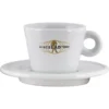 The Miscela dOro Modern Latte Cup & Saucer (9.5 fl oz) is a white ceramic cup with a handle, featuring a gold logo with the brand name and a coffee bean globe with a walking figure, set on a matching saucer. © 2025 1st-line.com