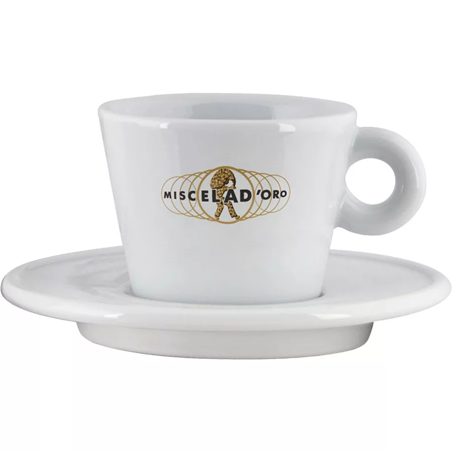 The Miscela dOro Modern Latte Cup & Saucer (9.5 fl oz) is a white ceramic cup with a handle, featuring a gold logo with the brand name and a coffee bean globe with a walking figure, set on a matching saucer. © 2025 1st-line.com