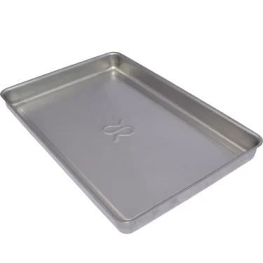 The Rancilio 32330365 Drip Tray is a rectangular, silver metal tray with slightly raised edges and a flat surface featuring a subtle embossed center design; shown empty and viewed at an angle. © 2025 1st-line.com