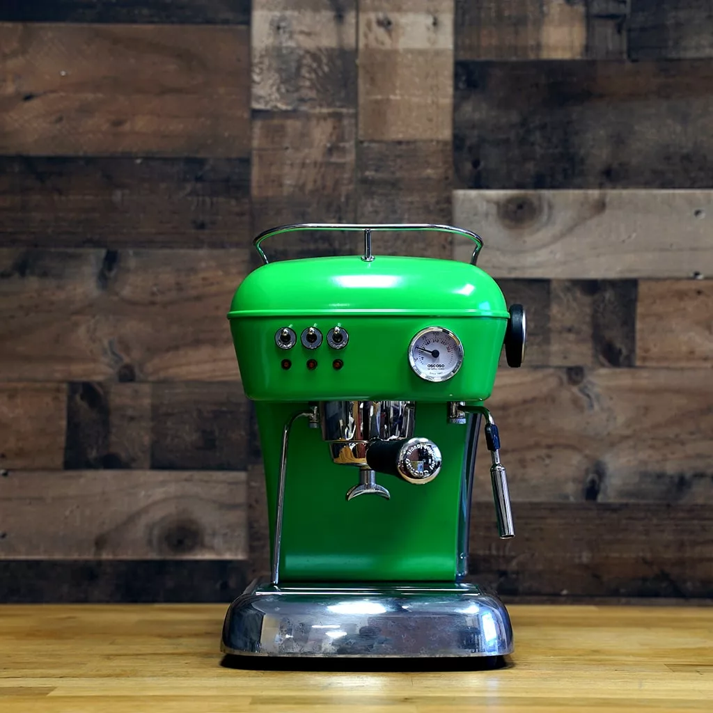 The (SOLD) SIDEWALK SALE - Ascaso Dream V1 UP Meadow Green Espresso Machine Tank/Reservoir (USED), featuring silver accents, sits on a wooden counter in front of a rustic plank wall, enhancing the space with charm and style. © 2025 1st-line.com