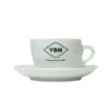 The VBM Cappuccino Cup & Saucer features a white ceramic cup with the black VBM logo and As once and never before text, placed on a matching saucer against a plain white background. © 2025 1st-line.com