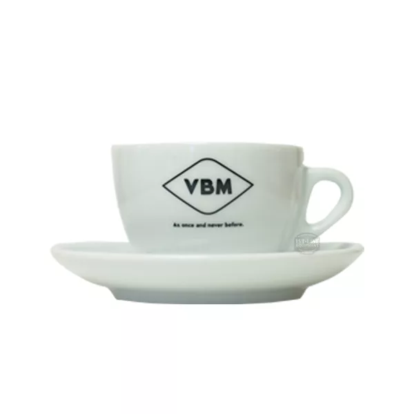 The VBM Cappuccino Cup & Saucer features a white ceramic cup with the black VBM logo and As once and never before text, placed on a matching saucer against a plain white background. © 2025 1st-line.com