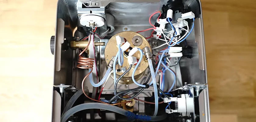 Top-down view inside the DISCONTINUED Lelit Victoria PL91T PID Single Boiler Espresso Machine, showing its metal boiler, wiring, tubes, and electronic components all neatly arranged on a wooden surface. © 2025 1st-line.com