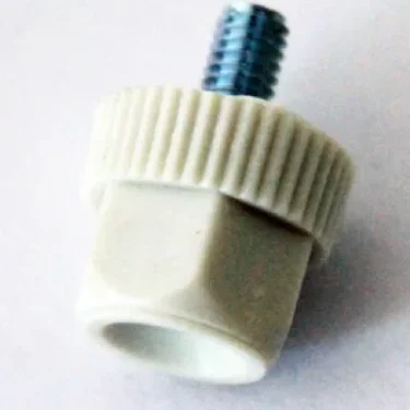 A close-up of the Lelit MC330 Screw Cap/Bolt for Chute shows a white plastic knob with a ridged edge, hexagonal base, and a metal threaded screw protruding from the top, placed on a light surface. © 2025 1st-line.com