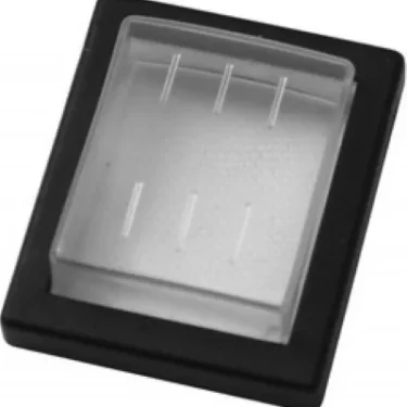 The Ascaso V..163 Water Tightness Cover is a rectangular black plastic base with a clear, slightly raised cover featuring four parallel ridges on top, resembling a protective cap or switch cover. © 2025 1st-line.com