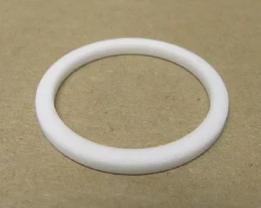 The VBM GUARCALDOM Heating Element Gasket, a white circular washer-like ring, lies flat on a plain brown surface—perfect as a replacement gasket for VBM machines. © 2025 1st-line.com