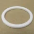 The VBM GUARCALDOM Heating Element Gasket, a white circular washer-like ring, lies flat on a plain brown surface—perfect as a replacement gasket for VBM machines. © 2025 1st-line.com