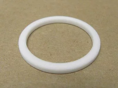 The VBM GUARCALDOM Heating Element Gasket, a white circular washer-like ring, lies flat on a plain brown surface—perfect as a replacement gasket for VBM machines. © 2025 1st-line.com