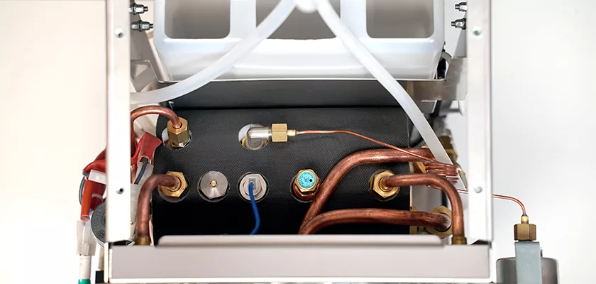 Close-up of the internal components of the DISCONTINUED La Nuova Era Cuadra HX Espresso Machine, showing copper pipes, fittings, wires, and a black insulated boiler inside its metal frame. © 2025 1st-line.com