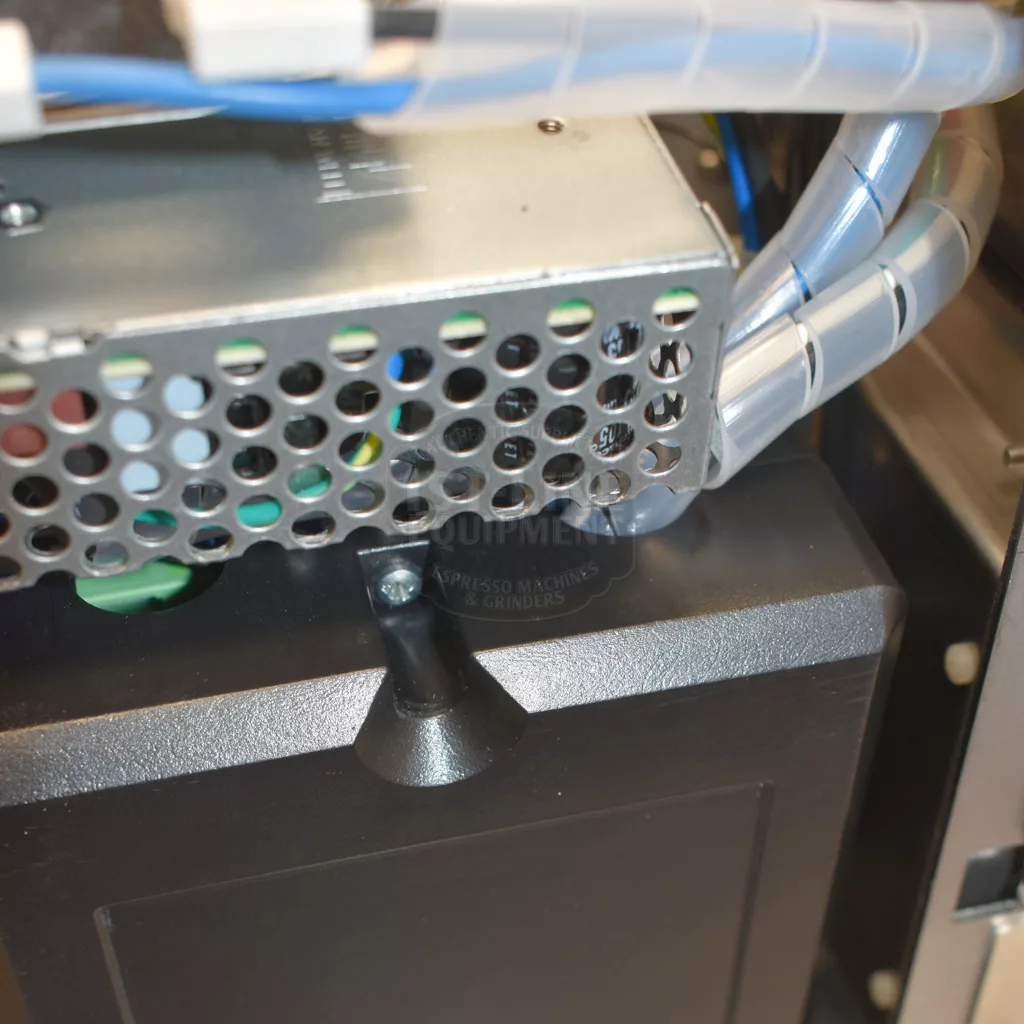 Close-up of a metal electronic component with a perforated panel, wiring, and black plastic base inside the Bezzera Matrix MN V2 Dual Boiler Espresso Machine, likely part of its advanced dual boiler system. © 2025 1st-line.com