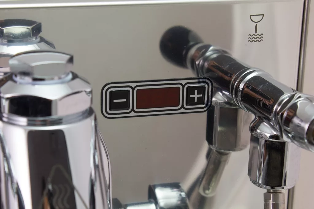 Close-up of a shiny metal Bezzera Mitica V2 HX Espresso Machine featuring a digital control panel with minus/plus buttons, red display, and a cup with steam symbol for the hot beverage function. © 2025 1st-line.com
