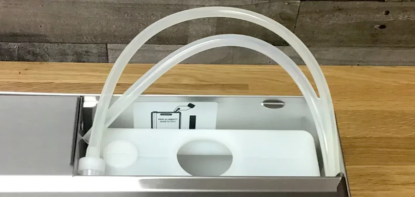 A close-up shows the white plastic water reservoir with two clear hoses inside the Lelit Elizabeth V3 Dual Boiler Espresso Machine, all placed on a wooden surface. © 2025 1st-line.com