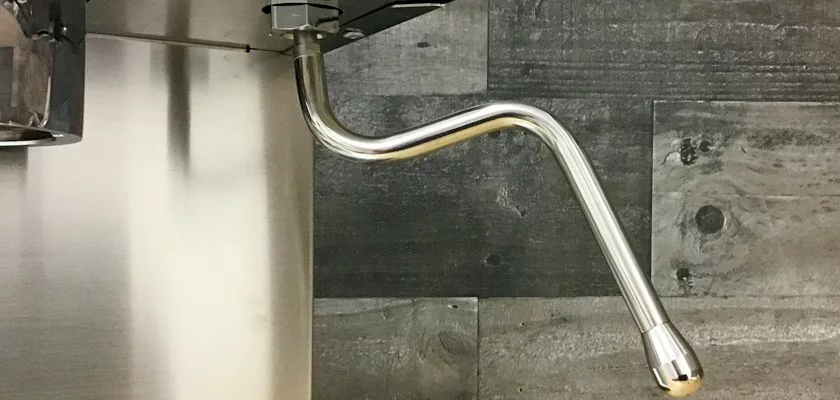 A shiny metal steam wand with a unique zigzag bend is attached to the side of a stainless steel Lelit Elizabeth V3 Dual Boiler Espresso Machine, set in front of a wooden textured wall. © 2025 1st-line.com