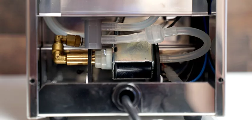 Close-up view of the internal components of the DISCONTINUED ECM Casa V Espresso Machine, showing tubes, wiring, and metal parts inside a sleek metal casing. © 2025 1st-line.com