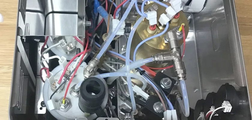 The interior of the Lelit Elizabeth V3 Dual Boiler Espresso Machine shows tubes, wires, metal elements, a brass boiler, and precise fittings—all compactly arranged on a metallic base. © 2025 1st-line.com