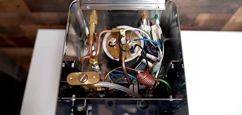 Top-down view of the internal components of the DISCONTINUED ECM Casa V Espresso Machine, featuring wires, copper tubes, brass fittings, and a central boiler within a metallic casing. © 2025 1st-line.com