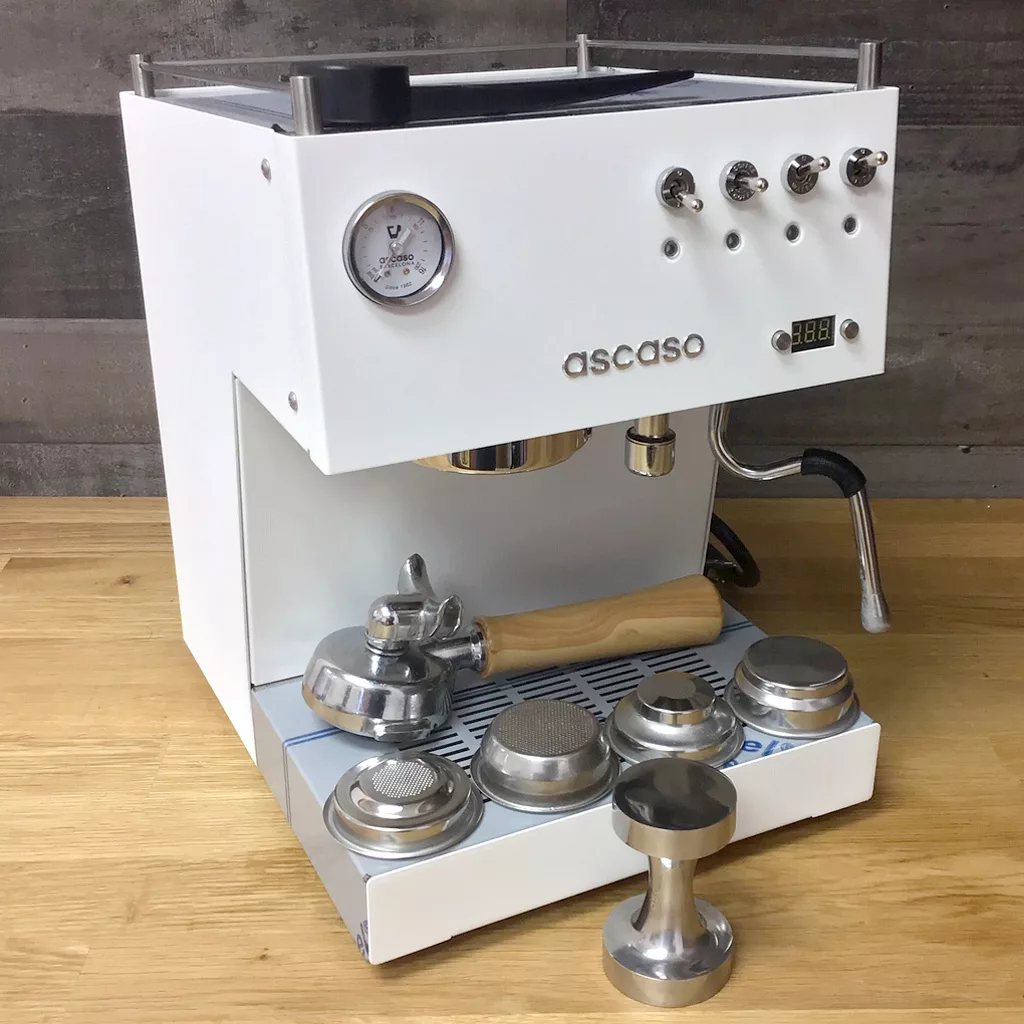 A SOLD Ascaso Steel Uno White PID Espresso Machine w/ Wood Handle & Steam Knob (showroom demo) sits on a wooden counter with a portafilter, tamper, and filter baskets. Features PID temperature control, pressure gauge, and switches. © 2025 1st-line.com