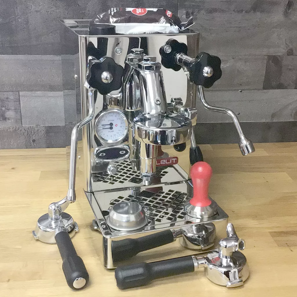 A SOLD Lelit Mara PL62T PID HX Espresso Machine (returned & refurbished) with a pressure gauge, steam wand, red handle tamper, and two portafilters sits on a wooden countertop against a gray tiled wall. © 2025 1st-line.com
