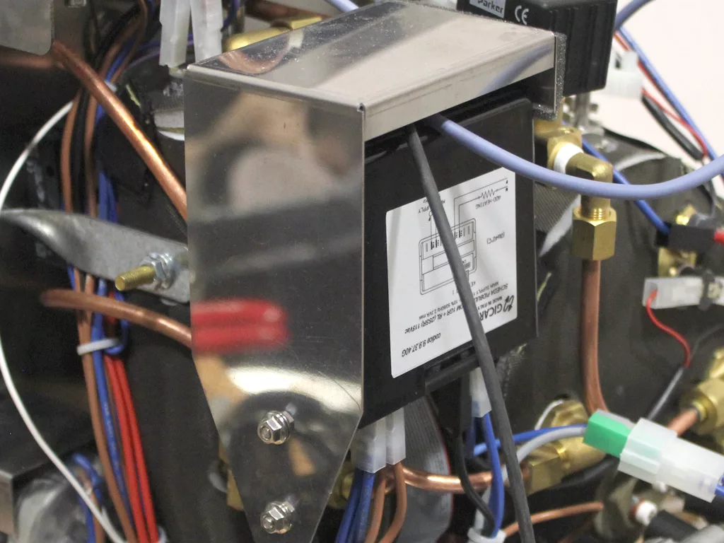 A close-up view of VBM Dual Boiler machinery with various wires, pipes, and a metallic component featuring a diagram label. The image highlights parts connected for a 3.5 to 4.0 conversion in electronic and mechanical systems. © 2025 1st-line.com