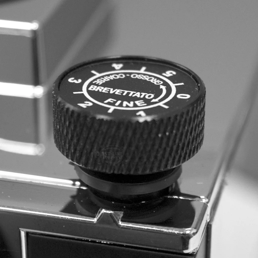 Close-up of a black adjustment dial on the metallic surface of a DISCONTINUED Eureka Mignon Silenzio 50mm Espresso Coffee Grinder, labeled BREVETTATO FINE with numbers 1–5 and directional arrows, shown in black and white. © 2025 1st-line.com