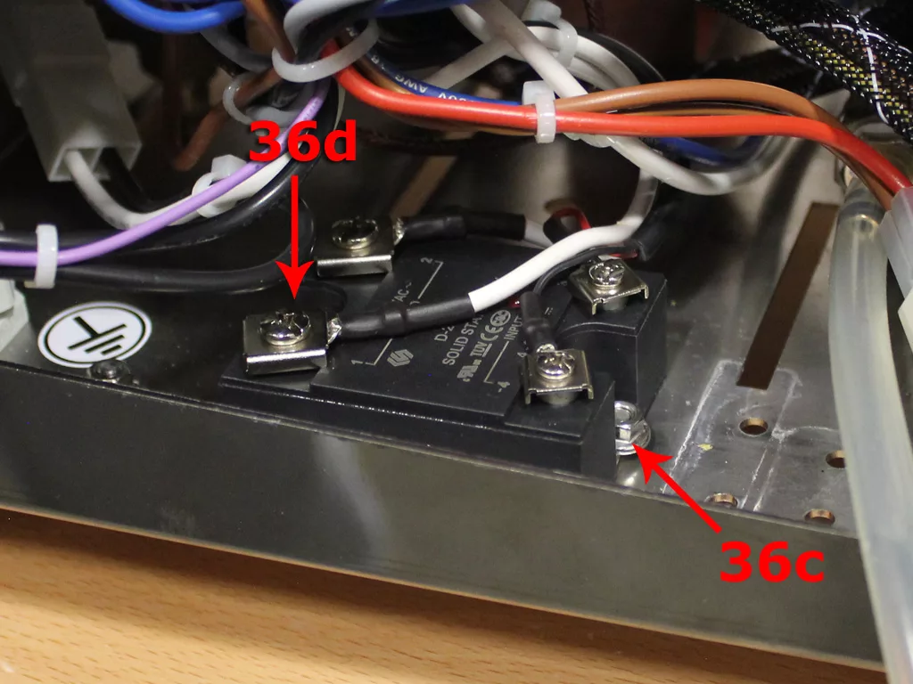Close-up of an electrical component from a VBM Dual Boiler, with multiple wires connected. Two red arrows labeled 36d and 36c point to different screw terminals, possibly part of a 3.5 to 4.0 conversion setup on a metal surface. © 2025 1st-line.com